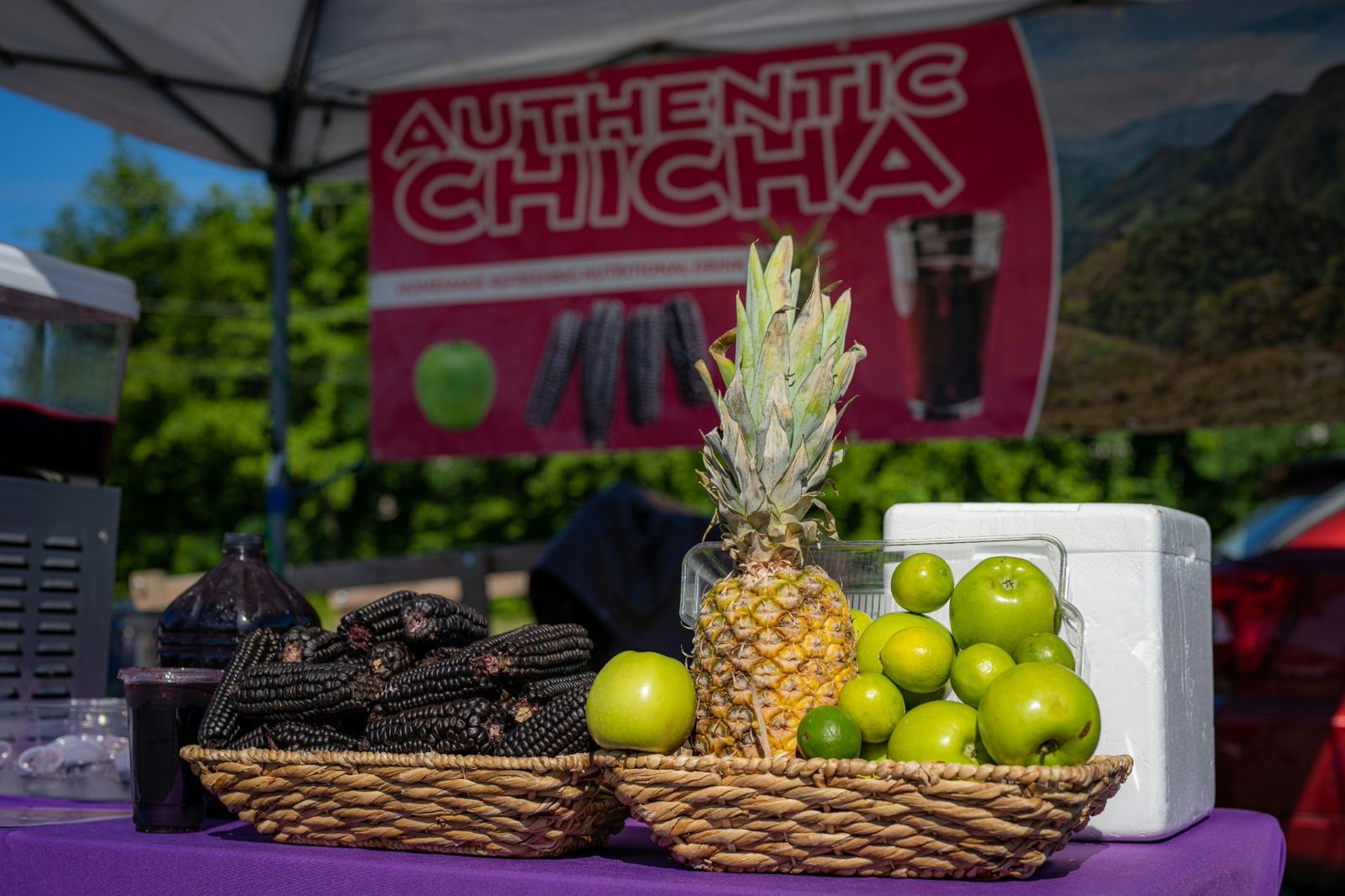 Authentic Chicha at a local farmers market with bottles of purple corn drink and fresh fruit